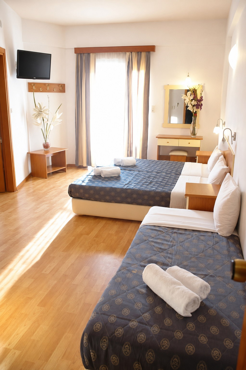 Bright triple room with wooden floors and sunlit windows at Hotel Filoxenia Beach