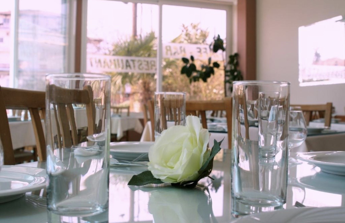 Close-up of an elegantly set restaurant table with a white rose centerpiece